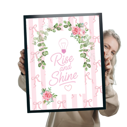 Person holding a framed motivational poster with 'Rise and Shine' text and decorative elements.